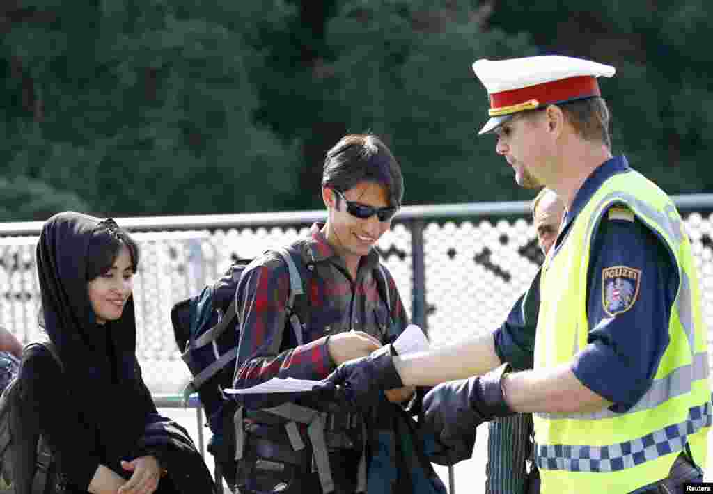 A policeman gives written instructions to migrants as they cross the border from Slovenia to Bad Radkersburg, Austria.