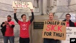 Whitney Walker, second left, and Tracy Kurzendoerfer protest outside of Kentucky Gov. Matt Bevin's office, March 30, 2018, in Frankfort, Ky. Walker and Kurzendoerfer are teachers in Fayette County. Both called in sick Friday to protest a bill lawmakers passed late Thursday that makes changes to the state's pension system.
