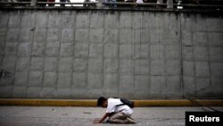 A woman kneels at the place where 17-year-old demonstrator Neomar Lander died during riots at a rally against Venezuelan President Nicolas Maduro's government in Caracas, Venezuela, June 8, 2017.