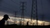 FILE - Men walk past electricity pylons as they return from work in Orlando, Soweto township, South Africa, March 18, 2019. 