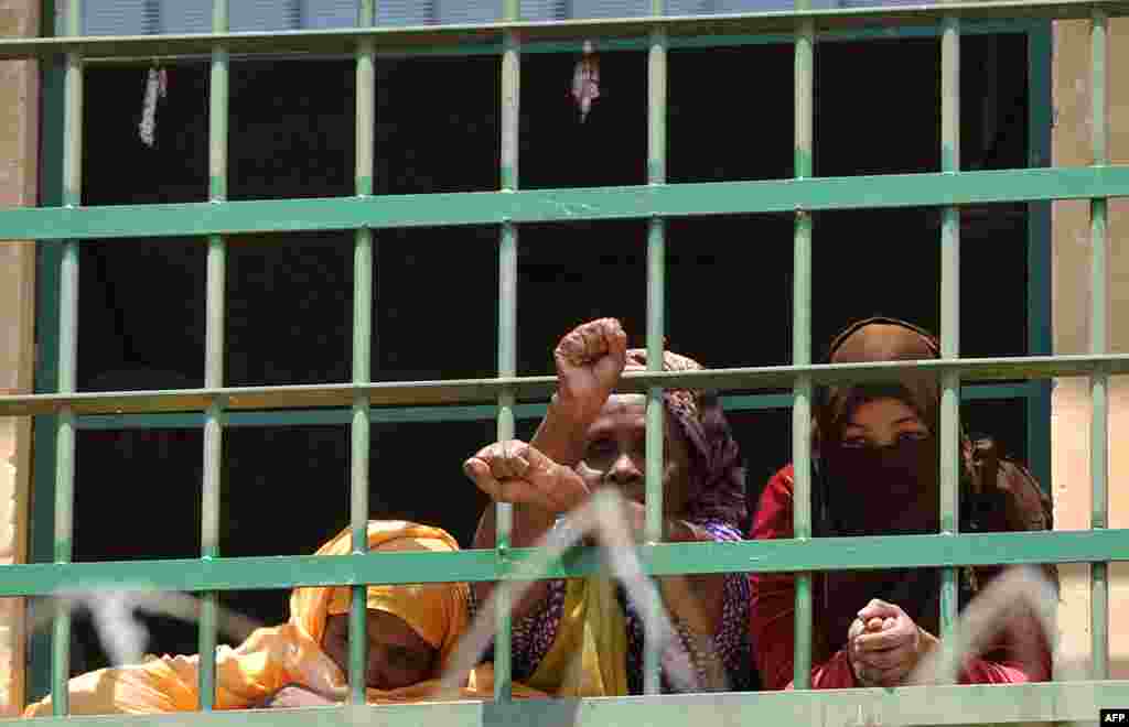 Migrants glance out of the windows at Lyster Barracks detention center in Malta&#39;s Hal Far disused airfield. Malta has seen an influx of irregular migrants in the past month with 769 arriving in July alone. 