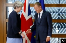 European Council President Donald Tusk, right, reaches out to shake hands with British Prime Minister Theresa May prior to a bilateral meeting on the sidelines of an EU summit in Brussels, June 22, 2017.