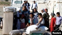 A boy sits on wheat flour as others stand by aid they received from a Saudi distribution center at a camp for internally displaced people (IDPs) near Marib, Yemen, Jan. 26, 2018.