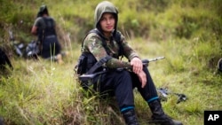 FILE - Juliana, a 20-year-old rebel fighter for the 36th Front of the Revolutionary Armed Forces of Colombia, or FARC, rests from a trek in the northwestern Andes of Colombia, in Antioquia state, Jan. 6, 2016. 