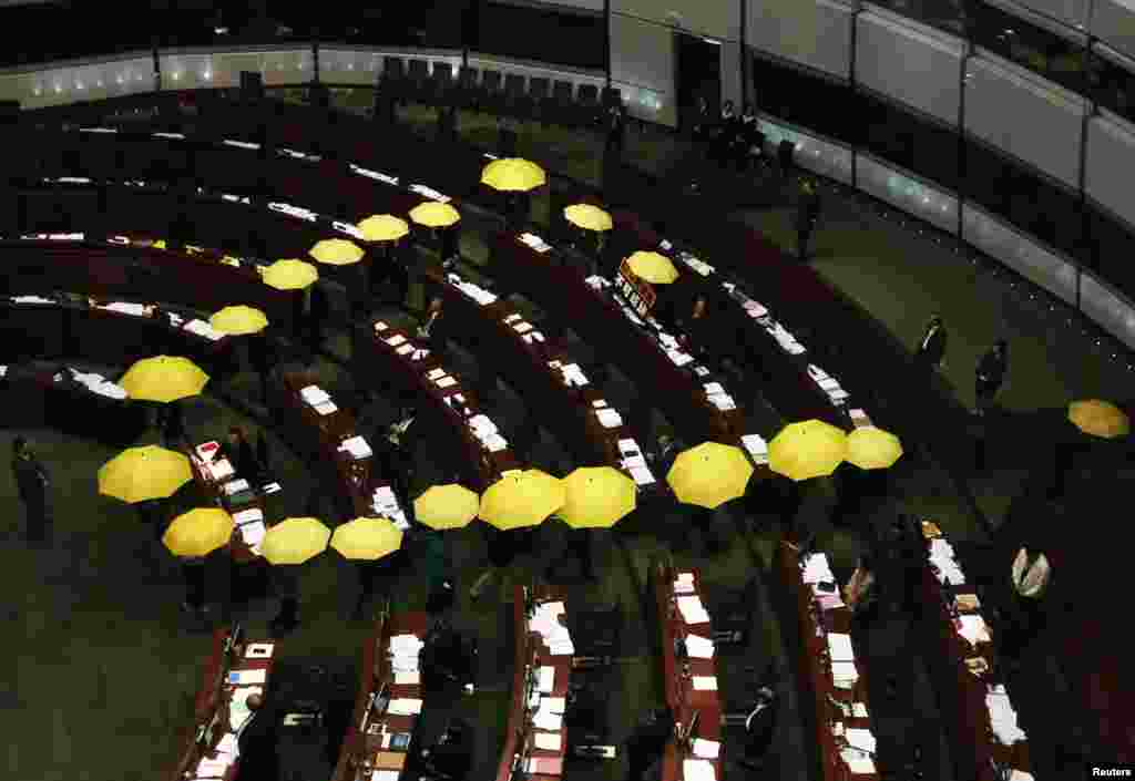 Pro-democracy lawmakers carrying yellow umbrellas, symbols for the Occupy Central movement, leave in the middle of a Legislative Council meeting as a gesture to boycott the government in Hong Kong.