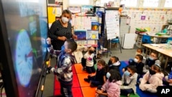 Kindergarten teacher Ana Zavala, at left, instructs students amid the COVID-19 pandemic at Washington Elementary School, Jan. 12, 2022, in Lynwood, Calif.