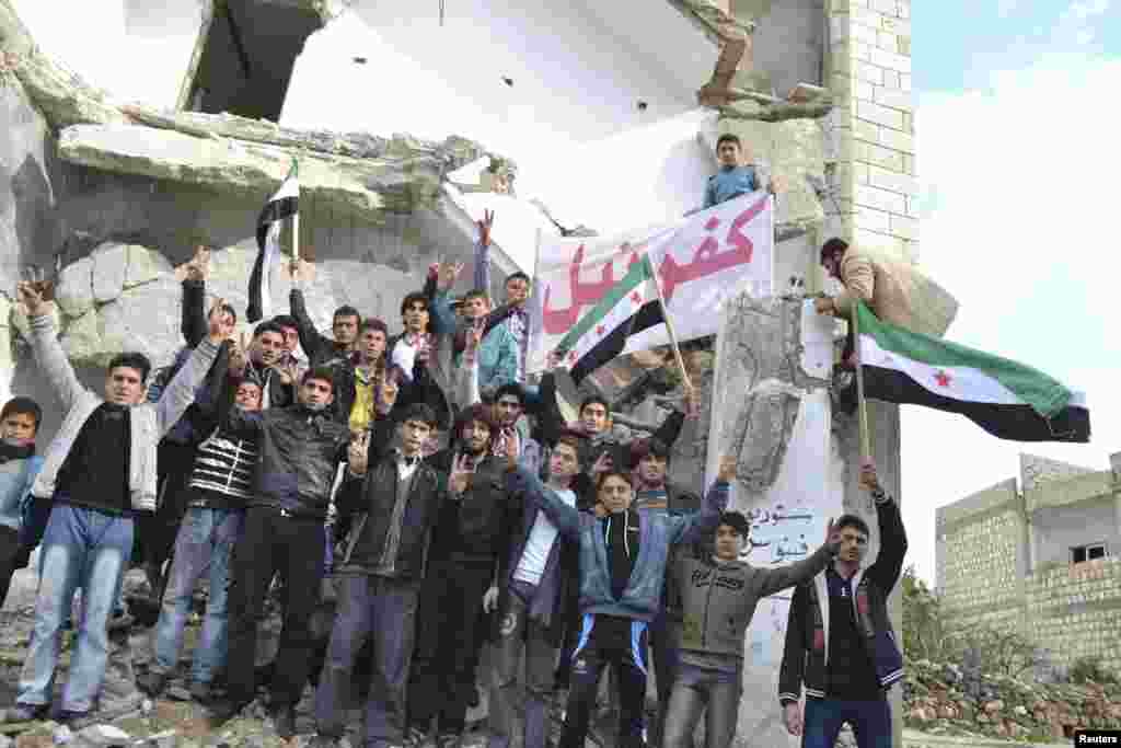 Demonstrators hold a placard during a protest against Syria&#39;s President Bashar al-Assad, after Friday prayers in Kafranbel near Idlib December 14, 2012. REUTERS/Raed Al-Fares/Shaam News Network/Handout (SYRIA - Tags: CIVIL UNREST MILITARY POLITICS CONFLIC