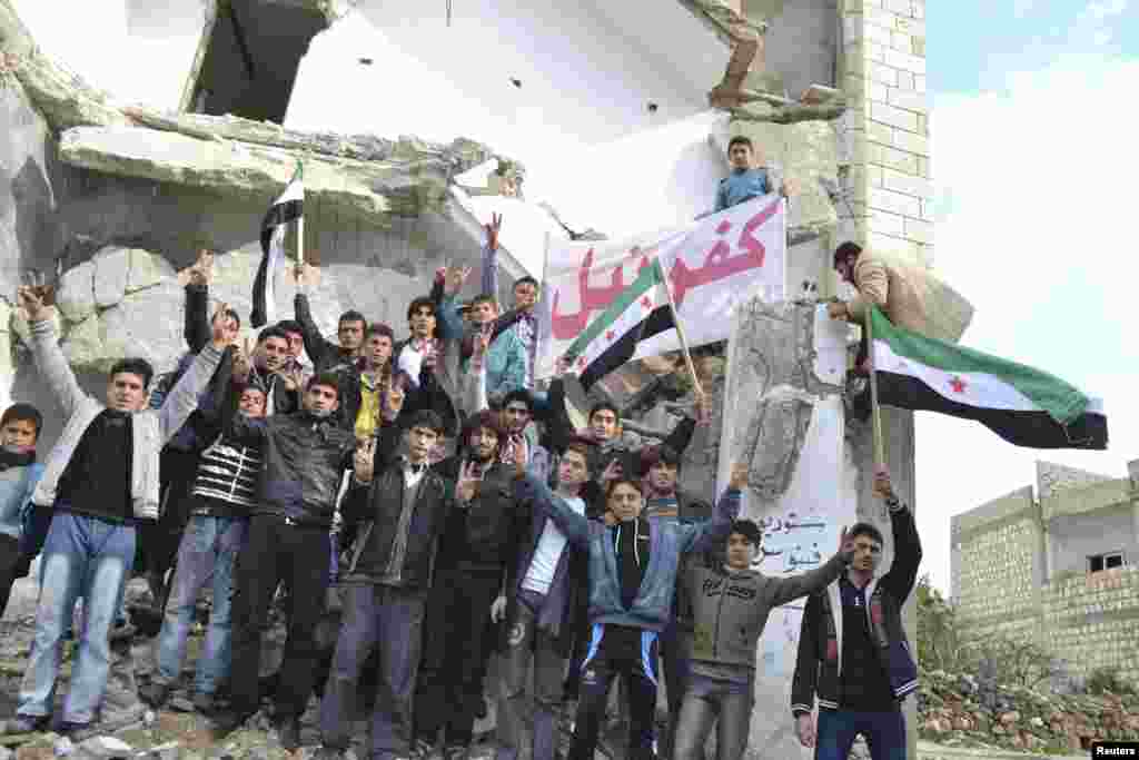 Demonstrators hold a placard during a protest against Syria's President Bashar al-Assad, after Friday prayers in Kafranbel near Idlib December 14, 2012. REUTERS/Raed Al-Fares/Shaam News Network/Handout (SYRIA - Tags: CIVIL UNREST MILITARY POLITICS CONFLIC
