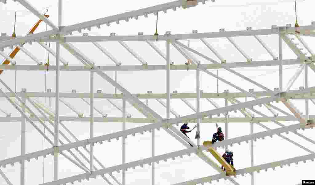 Workers on the roof of Arena Sao Paulo stadium, known as &quot;Itaquerao&quot;, which will host the opening match of the 2014 FIFA World Cup, in Sao Paulo, Brazil