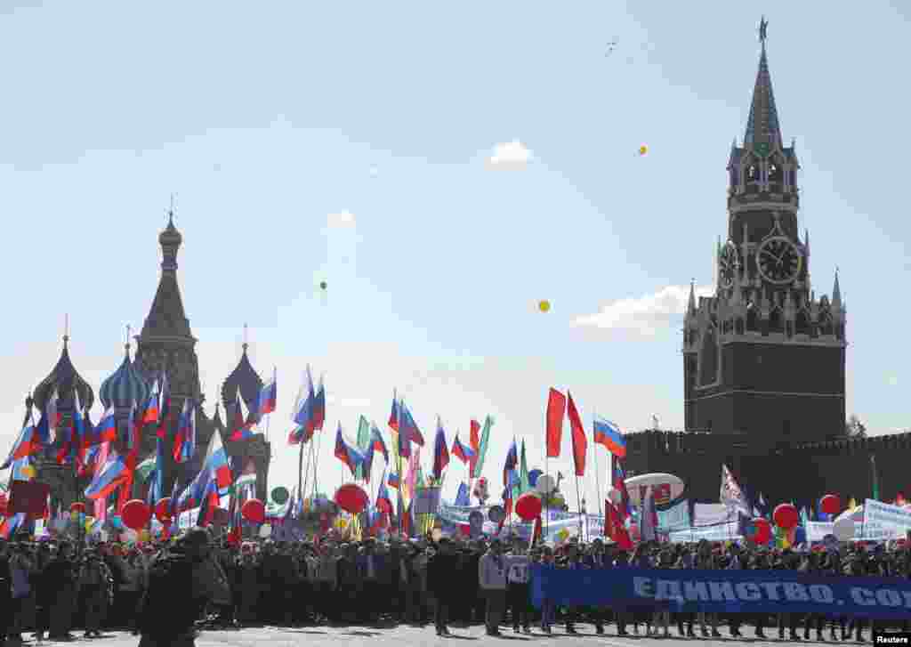 Pessoas caminham com bandeiras e cartazes pela Praça Vermelha em Moscovo, Rússia. 1 Maio, 2016.