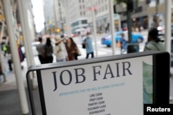 FILE - Signage for a job fair is seen on 5th Avenue in Manhattan, New York City, Sept. 3, 2021.