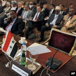 The Syrian flag and a sign in Arabic that reads, "the Syrian Arabic Republic," is seen in front of the empty chair of the Syrian representative during the Arab League Syria Group and foreign ministers meeting in Cairo, Egypt Sunday, February 12, 2012.