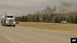 A truck drives by smoke from a wildfire near Fort McMurray, Alberta on Sunday, May 8, 2016.