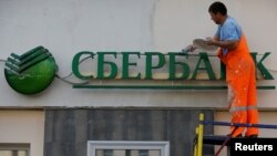 FILE - A worker paints the facade of a branch of Sberbank in central Moscow, Russia, Aug. 17, 2016.