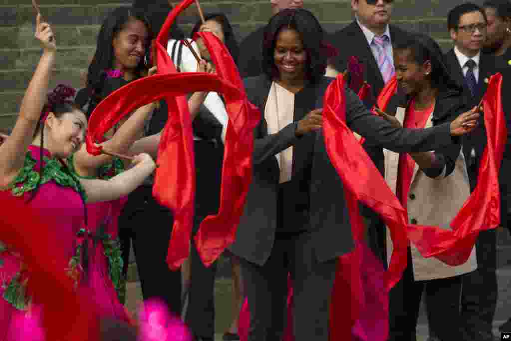 U.S. first lady Michelle Obama (c) dances with performers during her visit to Mutianyu section of the Great Wall of China in Beijing with her daughters Malia (2nd left), and Sasha (r). 