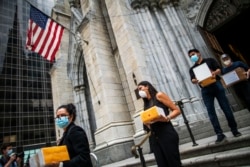 FILE - In this July 11, 2020, file photo, mourners carry out the remains of loved ones following the blessing of the ashes of Mexicans who died from COVID-19 at St. Patrick's Cathedral in New York.(AP Photo/Eduardo Munoz Alvarez, File)