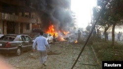 Seorang pria berjalan di dekat mobil yang terbakar pasca ledakan di dekat Kedutaan Iran di Beirut (19/11).