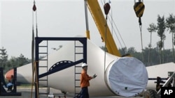 Workers prepare to lift a giant blade to be used as part of wind turbines at the Vestas Wind Technology Co. Ltd. factory in Tianjin, China, (File)