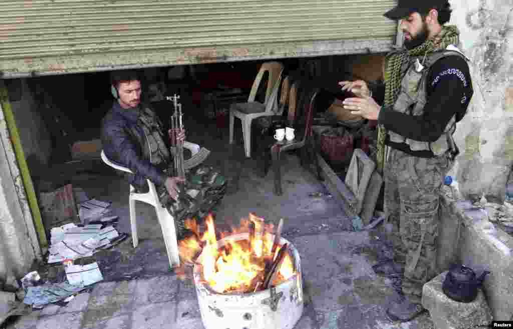 Free Syrian Army fighters warm themselves by a fire in Aleppo's al-Amereya district, December 11, 2012. 