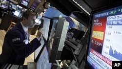 A television monitor shows the interest rate decision of the Federal Reserve as specialist Philip Finale works on the floor of the New York Stock Exchange, June 22, 2011.