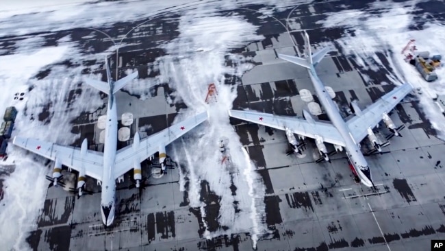 In this image taken from video provided by the Russian Defense Ministry Press Service, a pair of Tu-95 strategic bombers of the Russian air force are parked at an air base in Engels near the Volga River in Russia, Monday, Jan. 24, 2022. (Russian Defense M