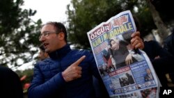 Một người đàn ông đưa ra trang nhất của nhật báo Ozgur với tiêu đề "can thiệp đẫm máu" khi mọi người tập trung bên ngoài trụ sở chính của tờ báo Zaman ở Istanbul, ngày 6 tháng 3 năm 2016.