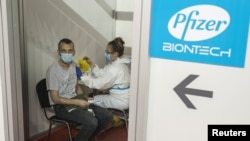 Seorang pria menerima dosis kedua vaksin Pfizer-BioNTech untuk melawan COVID-19 di aula tiga Belgrade Fair, di Beograd, Serbia, 13 April 2021. (Foto: REUTERS/Marko Djurica)