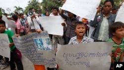 FILE - A boy holds a banner reading "Please stop grabbing our land" at a rally by evection victims in front of the National Assembly in Phnom Penh, Cambodia, Sept. 1, 2014.