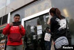 FILE - Drivers wait outside the office of taxi-hailing service Uber Inc. during a driver recruitment event in Hong Kong, China, Dec. 29, 2015.