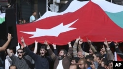 Jordanian supporters of the Islamic Action Front carry a national flag as they shout slogans during a protest in Amman, Jordan, February 25, 2011