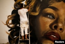 American artist, who goes by the name Drew works on his wall painting during an art happening, called POW! WOW! Israel, in the southern city of Arad, Israel, June 5, 2017.