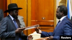 FILE - South Sudan's President Salva Kiir (L) and the country's rebel leader, Riek Machar, exchange signed peace agreement documents in Addis Ababa May 9, 2014.
