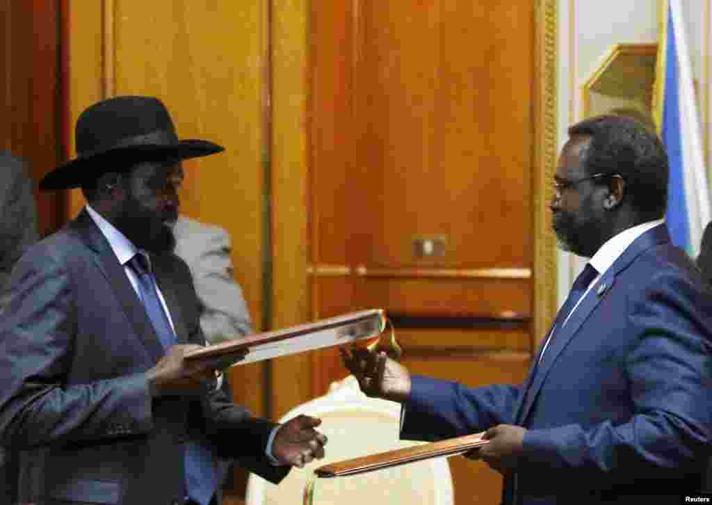 South Sudan's President Salva Kiir (L) and the country's rebel leader, Riek Machar, exchange a signed recommitment to cease fighting in Addis Ababa on May 9, 2014.