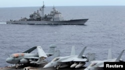 FILE - U.S. fighter jets on standby at the upper deck of a USS George Washington aircraft carrier while the USS Cowpens passes by, in the South China Sea, 170 nautical miles from Manila, September 2010.