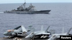 FILE - U.S fighter jets on standby at the upper deck of a USS George Washington aircraft carrier while the USS Cowpens passes by, in the South China Sea, 170 nautical miles from Manila, September 2010.