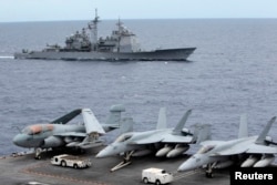 FILE - U.S fighter jets on standby on USS George Washington aircraft carrier while the USS Cowpens passes by, in the South China Sea, 170 nautical miles from Manila, Sept. 2010.