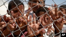 FILE - Syrian refugee children wave and flash the V-sign at a refugee camp in Suruc, on the Turkey-Syria border, June 19, 2015.