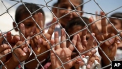 Syrian refugee children wave and flash the V-sign at a refugee camp in Suruc, on the Turkey-Syria border, June 19, 2015.