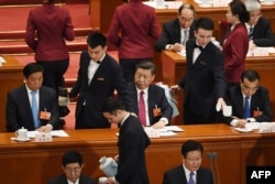 FILE - Chinese President Xi Jinping (C) looks on as his tea cup is replenished during the second plenary session of the National People's Congress in Beijing's Great Hall of the People on March 9, 2018.