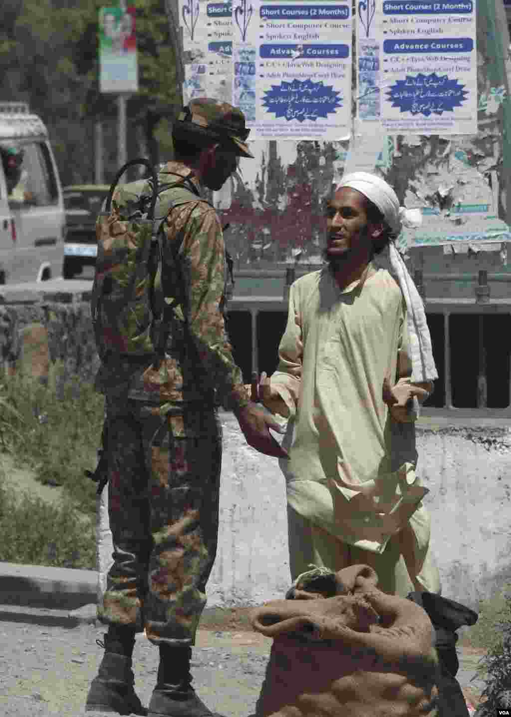 A soldier speaks to a man as he secures the area and clears the roads before the motorcade of Chinese Premier Li Keqiang.