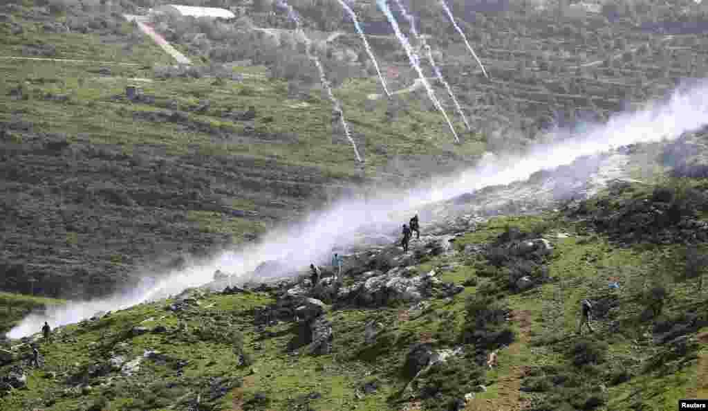 Demonstrators run as tear gas canisters are fired by Israeli security forces during clashes at a weekly protest against a nearby Jewish settlement, in the West Bank village of Nabi Saleh, near Ramallah. 