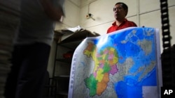 FILE - A worker holds a new officially approved map of China that includes the islands and maritime area that Beijing claims in the South China Sea, at a printing factory in Changsha in south China's Hunan province.