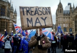 FILE - A pro-Brexit protester holds a banner as anti-Brexit protesters demonstrate outside the Houses of Parliament, ahead of a vote on Prime Minister Theresa May's Brexit deal, in London, Jan. 15, 2019.