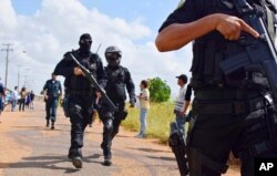 Heavily armed police officers walk outside the Agricultural Penitentiary of Monte Cristo, after dozens of inmates were killed, in Boa Vista, Roraima state, Brazil, Jan. 6, 2017.