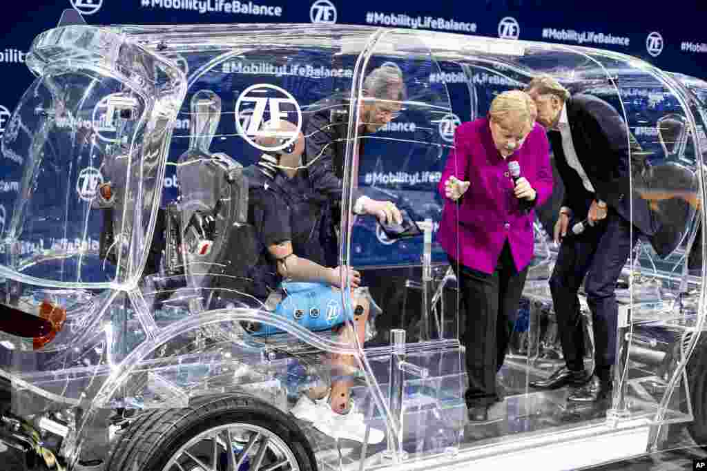 انگلا مرکل صدر اعظم آلمان در حال خروج از یک ماشین شفاف در نمایشگاه خودروی فرانکفورت.&nbsp;