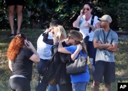 Anxious family members wait for news of students as two people embrace, Feb. 14, 2018, in Parkland, Fla.
