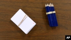 FILE - Slips of paper and pencils to be used by voters to select their candidates sit on a table before a Republican party caucus in Nevada, Iowa, Feb. 1, 2016.