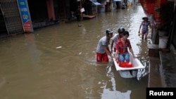 Men use a bathtub to ferry a woman on a flooded street caused by typhoon Kai Tak - RTR36XQY