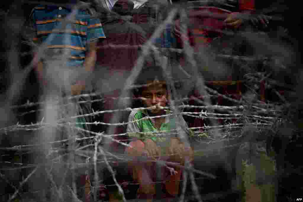 방글라데시와 인접한 라카인주 마웅다우 지역에 설치된 가시 철조망 너머로 로힝야족 난민 아이가 카메라를 응시하고 있다.&nbsp;&nbsp;