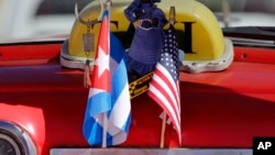 The stars and stripes and the Cuban national flag are placed together on the dashboard of a vintage American convertible in Havana, Cuba, Feb. 18, 2016.
